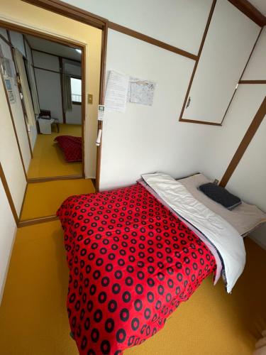 een kleine kamer met een rood bed in een kamer bij AnNam Stay Osaka Airport in Toyonaka