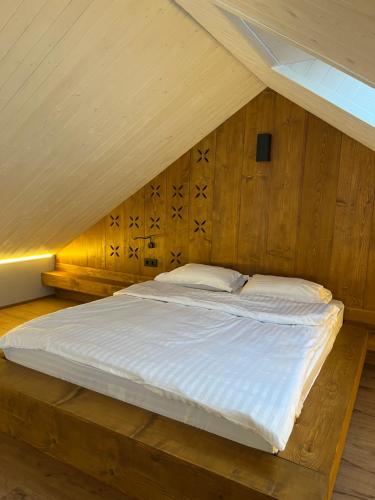 a bed in a room with a wooden wall at Котедж Stodola Slavsko in Slavske