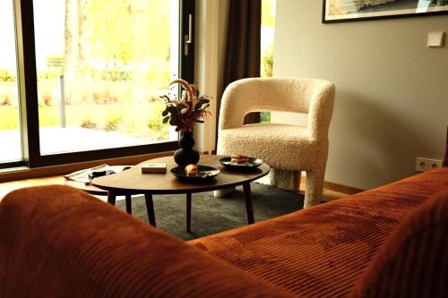 a living room with a couch and a chair and a table at bluestar apartments am Storkower See inkl Badesteg und Gartensauna in Hubertushöhe