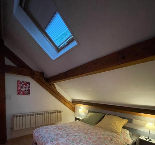 Schlafzimmer mit einem großen Bett und einem Dachfenster in der Unterkunft Le batelier du lac in Gérardmer