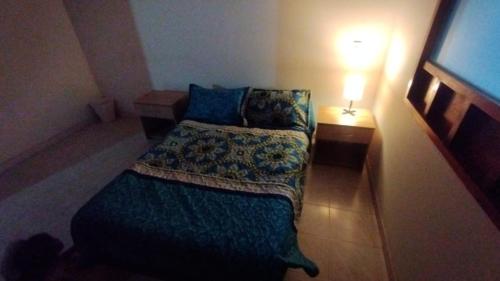 a small bedroom with a bed and a lamp at Mammamia CasaHotel in Duitama