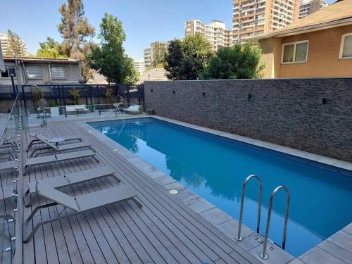 a swimming pool with chairs next to a building at Apartamento Nuevo Mall y metro Plaza Egaña in Santiago