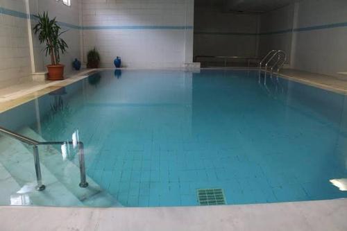 ein großer Pool mit blauem Wasser in einem Gebäude in der Unterkunft EMAN TERMAL HOTEL in Ilıcalı