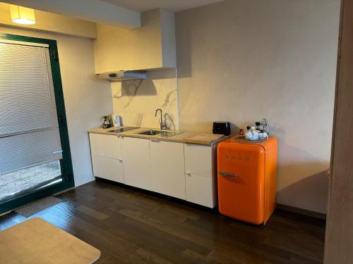 a kitchen with a sink and an orange refrigerator at Agriturismo Voeuja Lago Maggiore in Luino