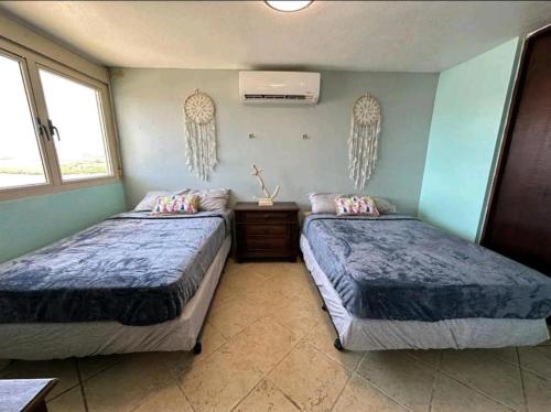 two beds in a room with two windows at Costa Bonita Apt in Culebra