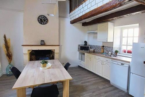 a kitchen with a wooden table and a kitchen with a fireplace at Maisonnette in La Croix-en-Touraine