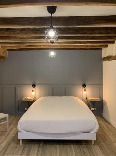 - une chambre avec un lit blanc et 2 tables dans l'établissement Gîte de la Forge, l'Atelier, à Fléré-la-Rivière