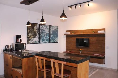 a kitchen with a bar with chairs and a tv at Cobertura Enseada de Zimbros in Bombinhas