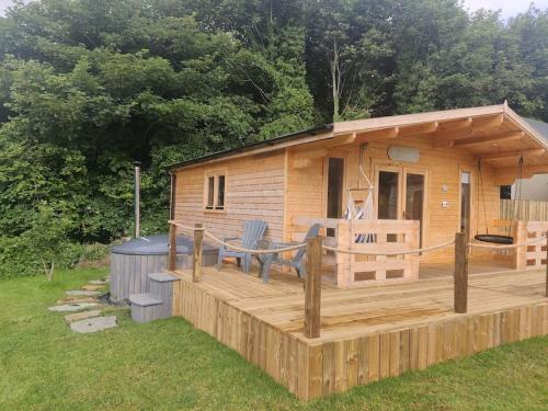 une cabane en rondins avec une terrasse et une véranda dans l'établissement Luxury log cabin with wood fired hot tub, à Moville
