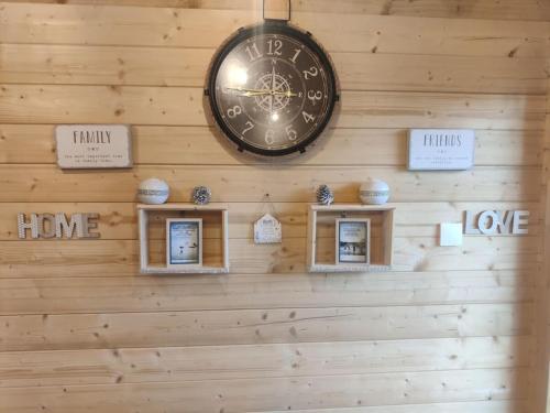 a clock hanging on a wooden wall with signs at Luxury log cabin with wood fired hot tub in Moville