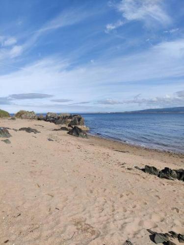 a beach with rocks and the ocean on a cloudy day at Luxury log cabin with wood fired hot tub in Moville