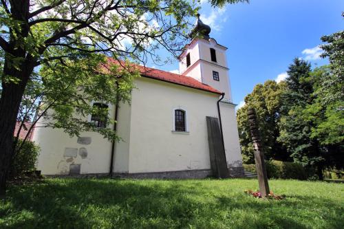 a white church with a tower on a green field at Gesztenyés Vendégház in Garáb