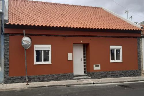 uma casa laranja com um telhado vermelho e um espelho em Casa dos Diogos em Grândola