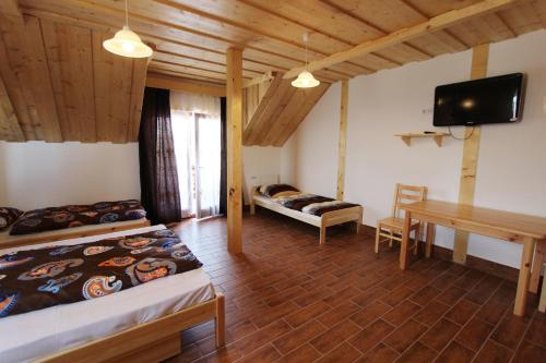 a room with two beds and a desk and a tv at Gesztenyés Vendégház in Garáb