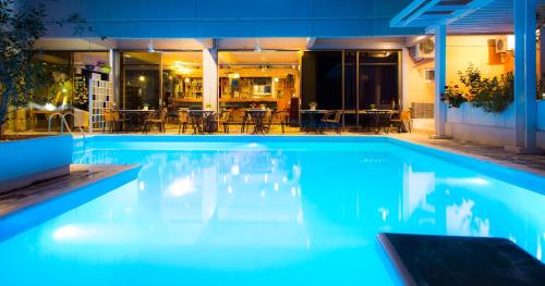 a swimming pool at night with a restaurant in the background at Apollonia Hotel Apartments in Varkiza
