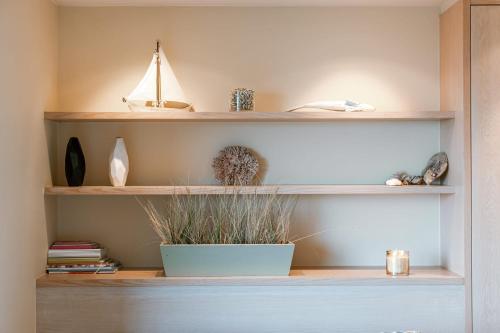 a shelf with a potted plant and books at Premium Holidays - Stylish appartement Villa Castelli with C-View at Nieuwpoort! in Oostduinkerke