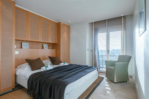 a bedroom with a bed and a chair and a window at Premium Holidays - Stylish appartement Villa Castelli with C-View at Nieuwpoort! in Oostduinkerke