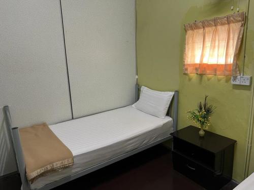 a small bed in a small room with a window at De Cameron Guest House in Tanah Rata