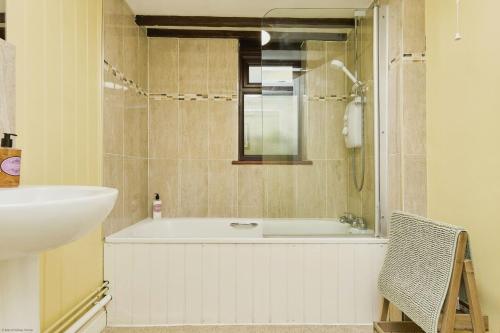 a bathroom with a bath tub and a sink at Lavender Cottage in Arreton