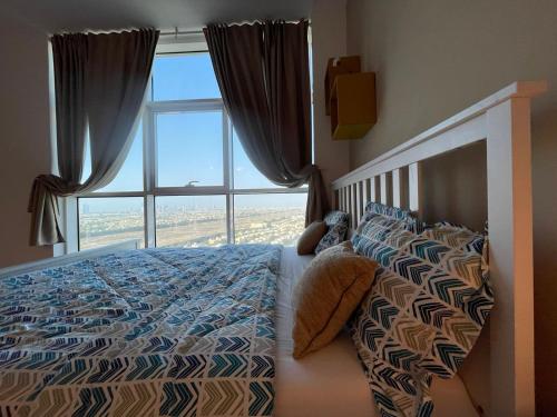 a bedroom with a bed and a large window at Studio apartment in Jumeriah village triangle in Dubai