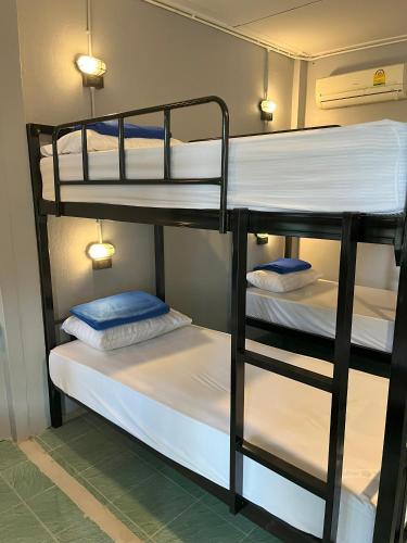 two bunk beds in a room with white sheets and blue pillows at Revolution Pai In Town in Pai