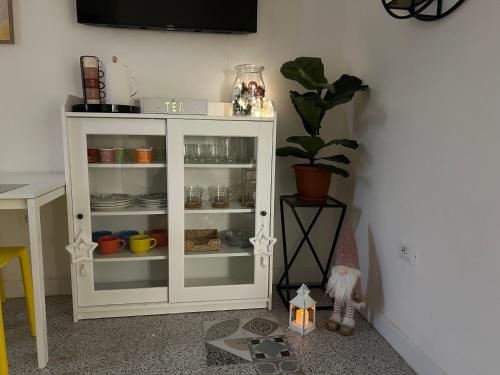 a white cabinet with dishes and a plant in a room at 8+8 Appartamento con garage in Livorno