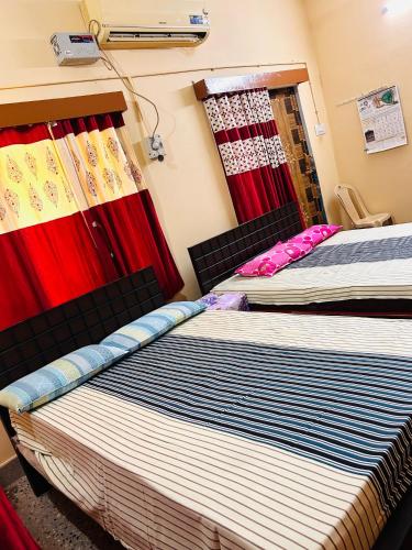 two beds sitting next to each other in a room at Sirvachur madhurakalli amman guest house in Perambalūr