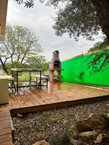 a wooden deck with a green wall behind it at Jordan River Village in Menaẖemya