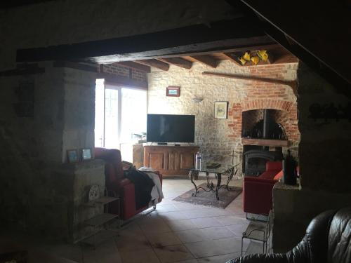 un salon avec une cheminée et une télévision dans l'établissement Gîte de Sauvagnac, à Cavagnac