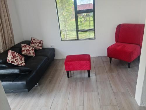 een woonkamer met een zwarte bank en een rode stoel bij Bakoena's full house in Newcastle