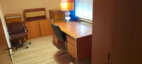 an office with a desk with two chairs and a lamp at Ferienwohnung Aue Deußen in Erftstadt