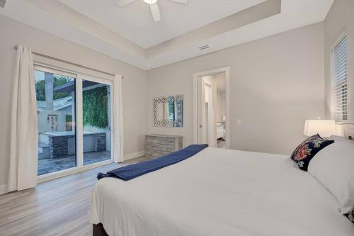 a white bedroom with a bed and a large window at Courtyard Home with Pool, Spa & Sauna close to Beach & City Center in Sarasota