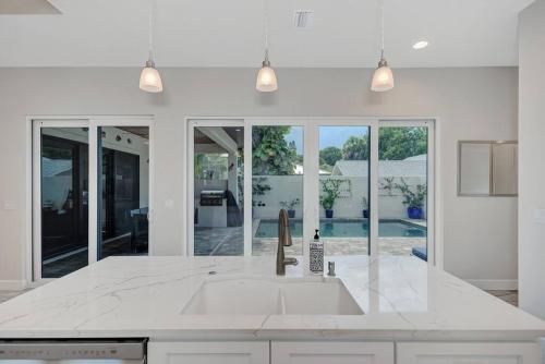 uma cozinha branca com um lavatório e uma grande janela em Courtyard Home with Pool, Spa & Sauna close to Beach & City Center em Sarasota