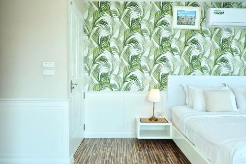 um quarto com uma cama com papel de parede tropical em The Beach Bangsaen by Thanthita next to Wonnapa beach em Bangsaen