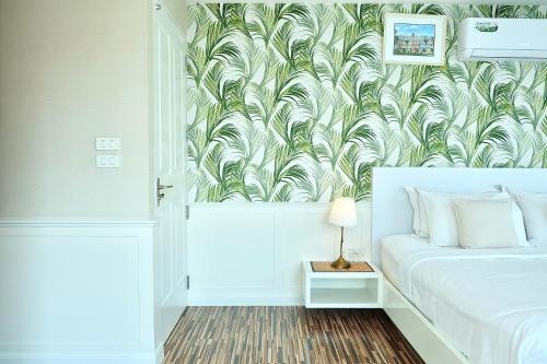 a bedroom with a bed with a tropical wallpaper at The Beach Bangsaen by Thanthita next to Wonnapa beach in Bangsaen