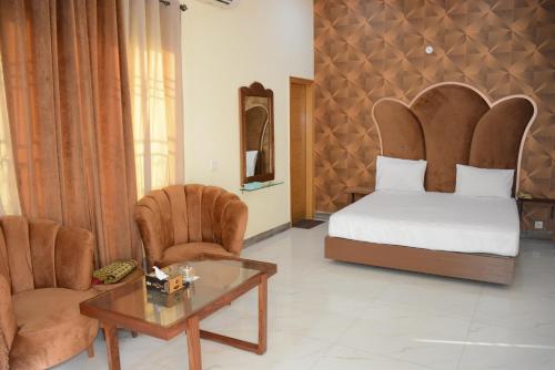 木爾坦的住宿－Hotel The Taj Multan，卧室配有一张床和一张桌子及椅子