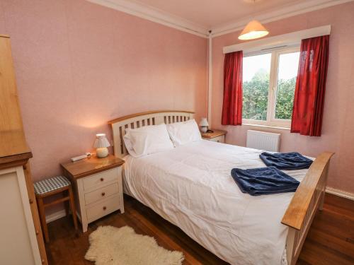 a bedroom with a bed and a window with red curtains at The Shingles in Sandown