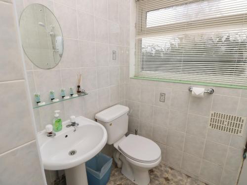 een badkamer met een toilet, een wastafel en een spiegel bij The Shingles in Sandown