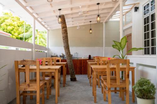 comedor con mesas y sillas de madera en Biosphere Inn, en Dharavandhoo