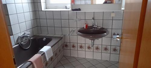 La salle de bains est pourvue d'un lavabo et d'une baignoire. dans l'établissement Ferienwohnung Aue Deußen, à Erftstadt