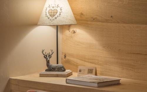 a lamp on a table with a book and a deer statue at Hotel Aran La Abuela in Vielha