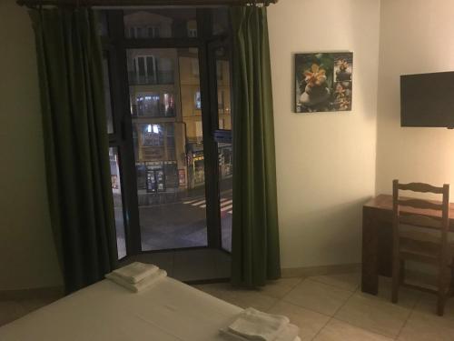 a room with a bed and a window with green curtains at Hotel Couleurs Sud Centre-ville Gare Charleville-Mézières in Charleville-Mézières