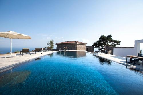 einen Pool mit Sonnenschirm und einigen Stühlen in der Unterkunft Momos Otel in Ayvacık