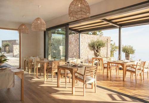 een restaurant met houten tafels en stoelen en grote ramen bij Momos Otel in Ayvacık