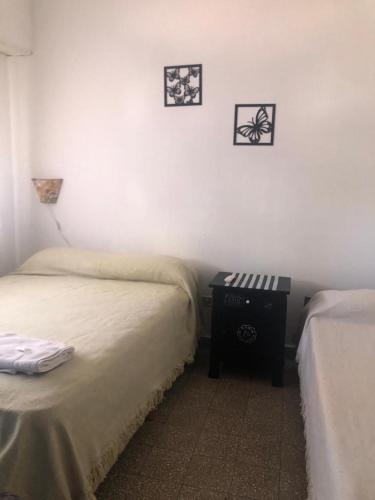 1 dormitorio con 2 camas y mesita de noche con 2 cuadros en la pared en Hotel CheMar en Necochea