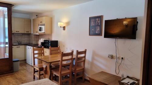 une cuisine avec une table et des chaises et une télévision dans l'établissement Crocus Résidence Cybele, à Brides-les-Bains