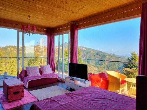 a bedroom with a large window with a view at Fairmont cottage Mukteshwar in Mukteshwar
