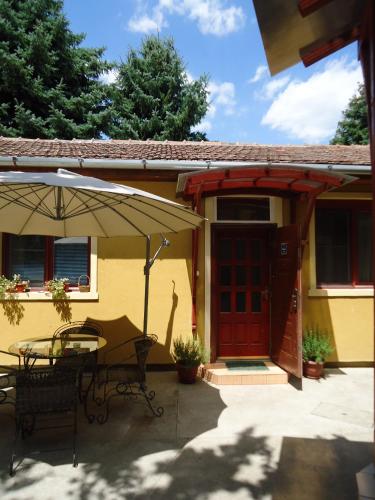 a patio with a table and an umbrella at Prenoćište Vila Stara Breza in Palić