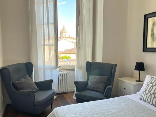 1 dormitorio con 2 sillas, 1 cama y 1 ventana en Santa Rosa Florence Apartments 3 Bedrooms - Private Parking en Florence
