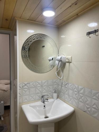 a bathroom with a sink and a mirror at Mamuka Chartolani Guesthouse in Mestia